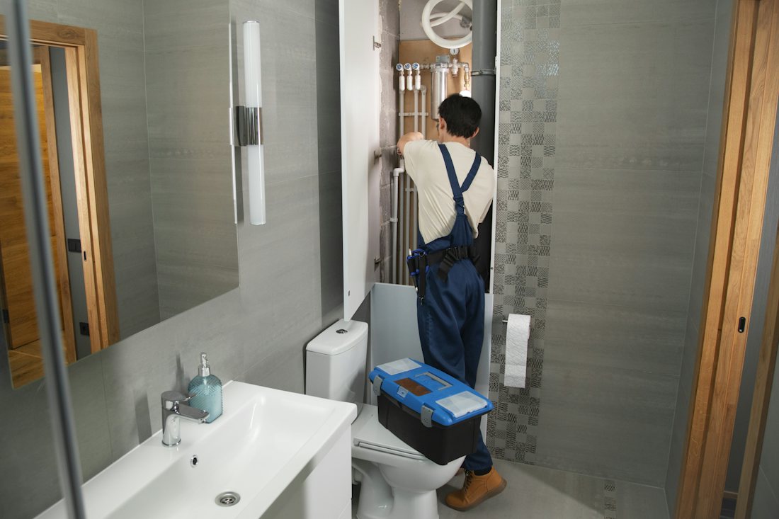 Plumber working on bathroom pipes